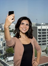 Mixed race businesswoman taking cell phone picture