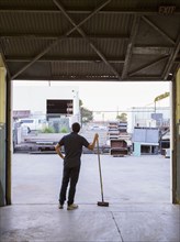 Worker holding broom in warehouse