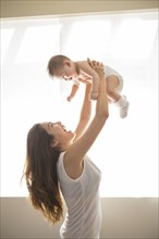 Mother lifting baby girl overhead