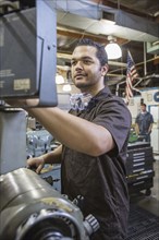 Hispanic worker operating machinery in factory