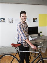 Caucasian architect wheeling bicycle in office