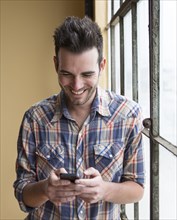 Caucasian man using cell phone by window
