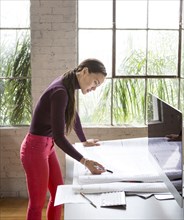 Mixed race architect examining blueprints in office