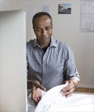 African American architect examining blueprints in office