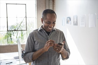 African American architect using cell phone in office