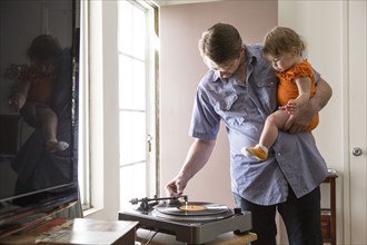 Caucasian father playing records with daughter