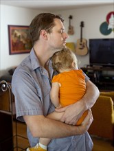 Caucasian father cradling toddler daughter