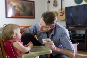 Caucasian father feeding toddler daughter