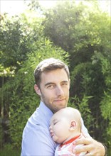 Caucasian father holding baby in backyard