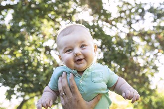 Caucasian baby lifted in air outdoors