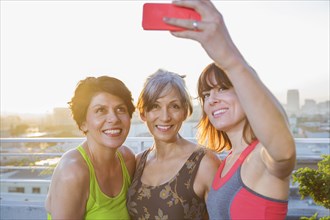 Women taking cell phone selfie on urban rooftop