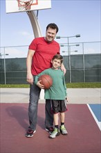 Caucasian father and son playing on basketball court