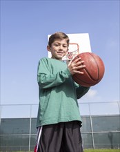 Low angle view of Caucasian boy holding basketball on court