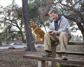 Caucasian man and dog sitting on picnic table in park