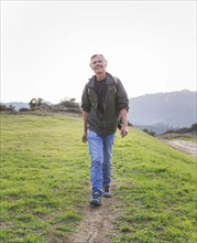 Older Caucasian man walking on dirt trail
