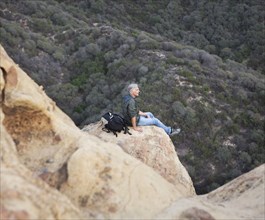 High angle view of older Caucasian man sitting on rock formation