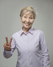 Older Japanese woman making peace sign