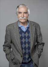 Older Caucasian man standing with hands in pockets