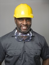 African American construction worker wearing hard hat and goggles