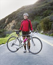 Caucasian woman holding bicycle on remote mountain road