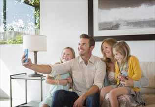 Caucasian family taking selfie on sofa