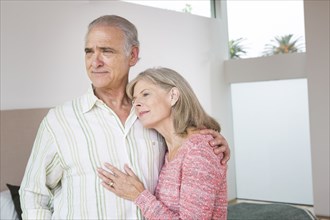 Older Caucasian couple hugging in living room