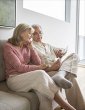 Older Caucasian couple using digital tablet on sofa