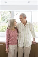 Older Caucasian couple hugging in kitchen