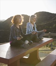 Caucasian women meditating on hilltop