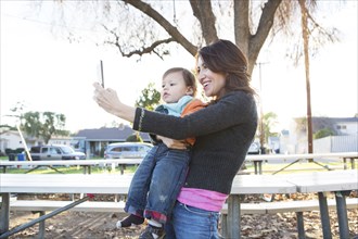 Hispanic mother taking selfie with son in park