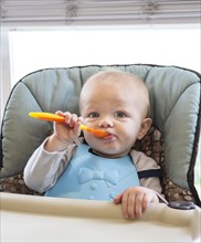 Caucasian baby boy eating in high chair