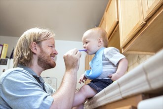 Caucasian father feeding son on kitchen counter