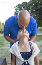 Father kissing forehead of daughter in park