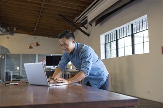 Mixed race businessman working on laptop in office