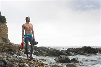 Hispanic diver wearing wetsuit on beach