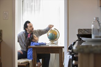 Hispanic father and daughter examining globe
