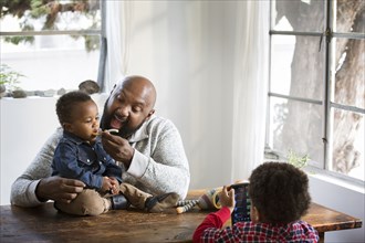Father feeding baby son at table