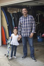 Hispanic father and daughter smiling in garage