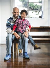 Mixed race father and son smiling at table
