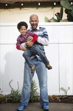 Mixed race father holding son outdoors