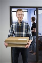 Caucasian businessman carrying packages in office