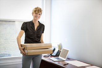 Caucasian businesswoman holding package in office