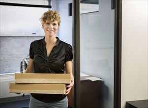 Caucasian businesswoman holding packages in office