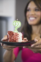 Mixed race woman holding cake with question mark candle