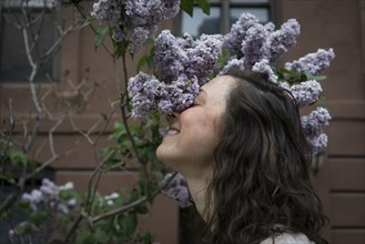 Caucasian woman smelling flowers on city street