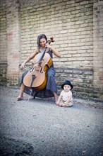 Mixed race musician playing cello with baby daughter