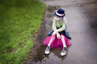 Caucasian girl wearing sneakers and tutu in puddle