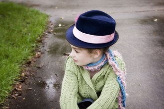 Caucasian girl wearing fedora hat on rainy concrete