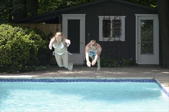 Couple diving into swimming pool in backyard