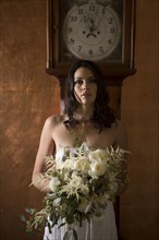 Bride holding bouquet of flowers under grandfather clock